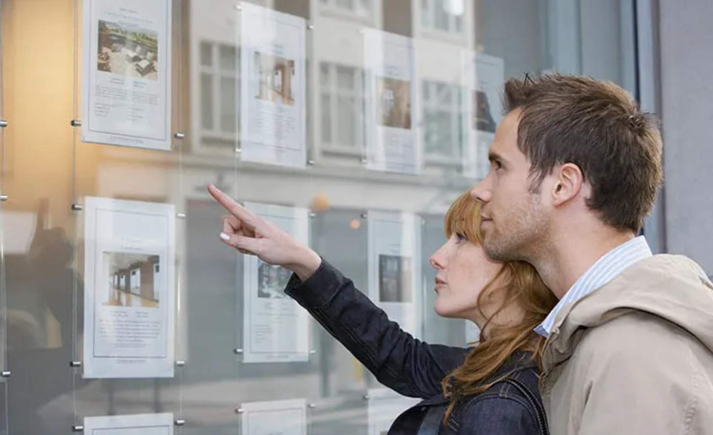 A couple browsing listings in an estate agent's window
